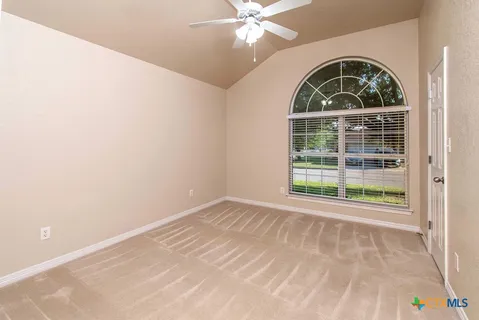 an empty room with wooden floor fan and windows