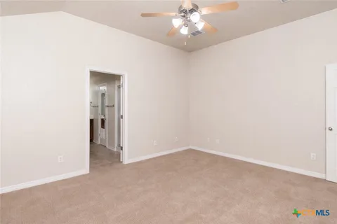 an empty room with a chandelier fan and windows
