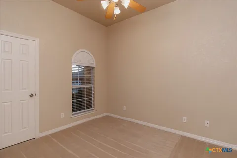 an empty room with windows and ceiling fan