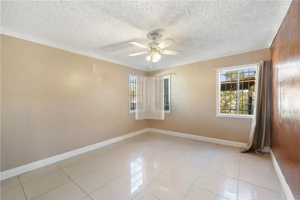 an empty room with windows and fan chandelier fan