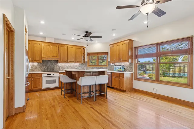 a kitchen with stainless steel appliances granite countertop a stove top oven a refrigerator a sink and white cabinets with wooden floor