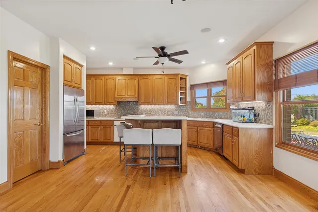 a kitchen with stainless steel appliances a dining table chairs and wooden floor