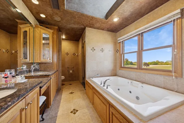 a bathroom with a bathtub a double vanity sink a vanity a window and a shower
