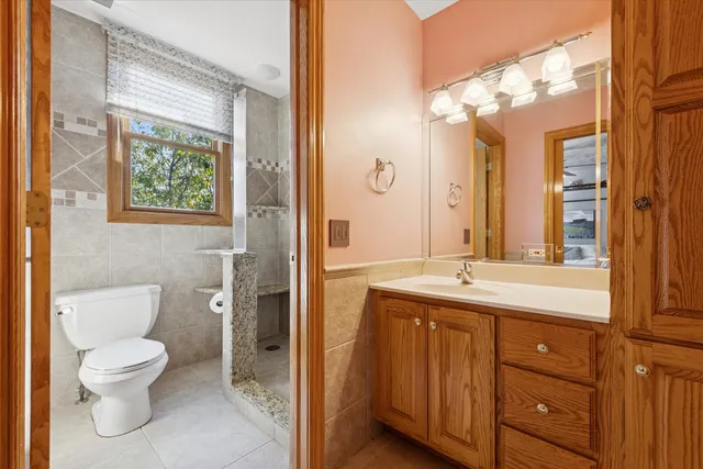 a bathroom with a granite countertop toilet a sink and a large mirror