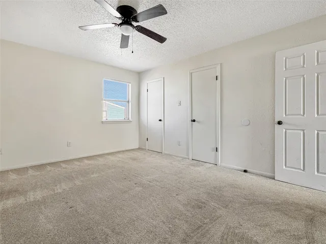 an empty room with wooden floor ceiling fan and windows