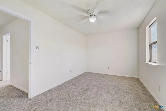 an empty room with a window and a ceiling fan