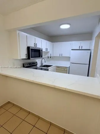 a kitchen with kitchen island a stove a sink a microwave and a refrigerator