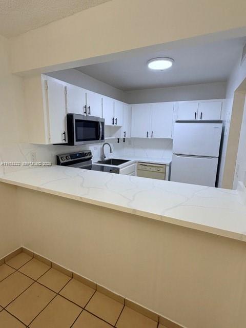 8990 Southwest 24th Street, Unit 215 Miami, FL 33165 - Photo 21 of 22 a kitchen with kitchen island a stove a sink a microwave and a refrigerator