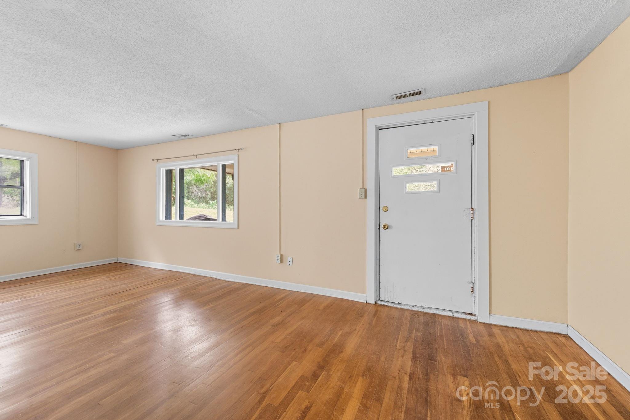 132 Little Knob Road Asheville, NC 28803 - Photo 7 of 18 an empty room with wooden floor and windows