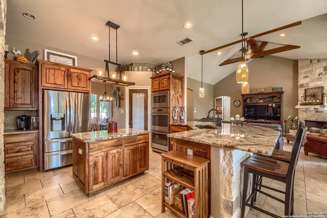 a kitchen with stainless steel appliances kitchen island granite countertop a table chairs and a refrigerator