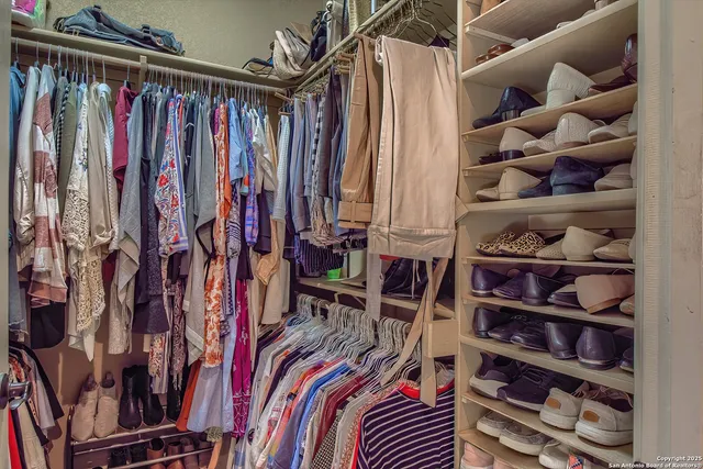 a view of walk in closet with clothes and shoes