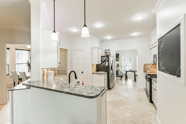 a kitchen with stainless steel appliances kitchen island granite countertop a stove top oven a sink dishwasher a refrigerator and white cabinets with wooden floor
