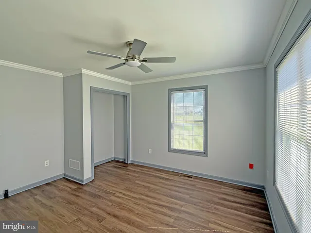a view of an empty room with a window and wooden floor