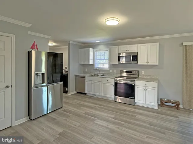 a kitchen with stainless steel appliances granite countertop a stove top oven a sink dishwasher a dining table and chairs with wooden floor