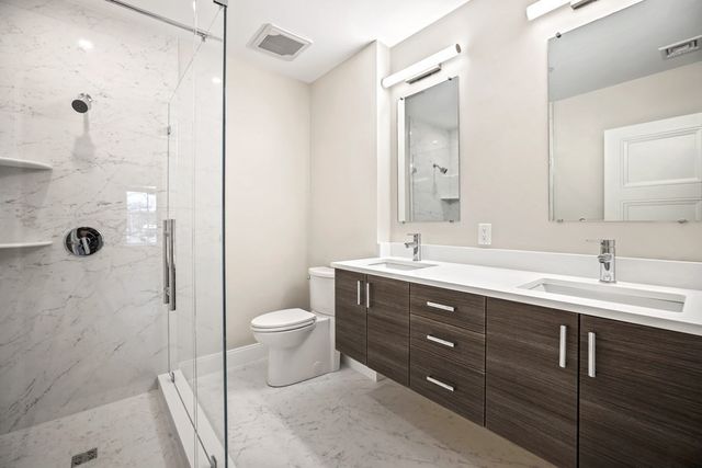 a bathroom with a double vanity sink toilet and shower