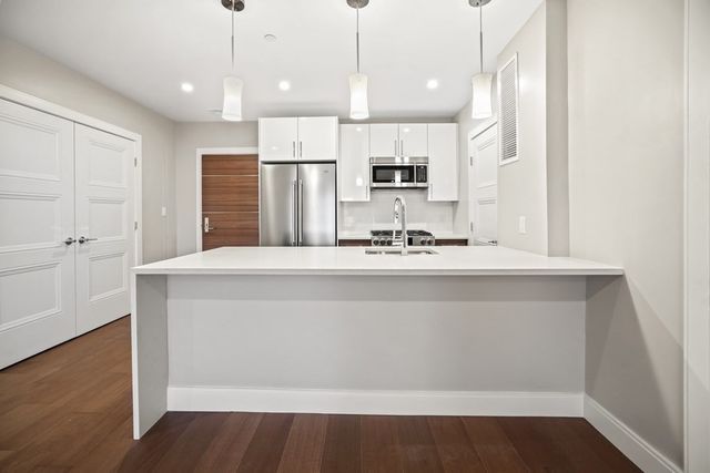 a kitchen with kitchen island white cabinets and stainless steel appliances