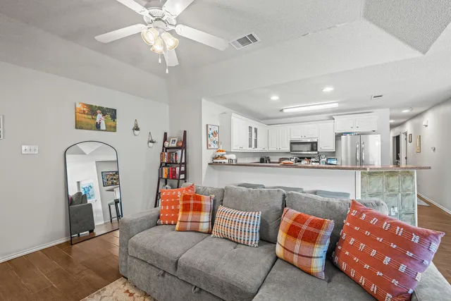 a living room with furniture kitchen view and a chandelier