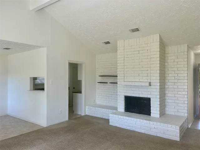 an empty room with windows and fireplace