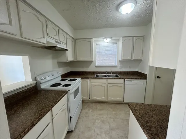 a kitchen with granite countertop white cabinets and sink