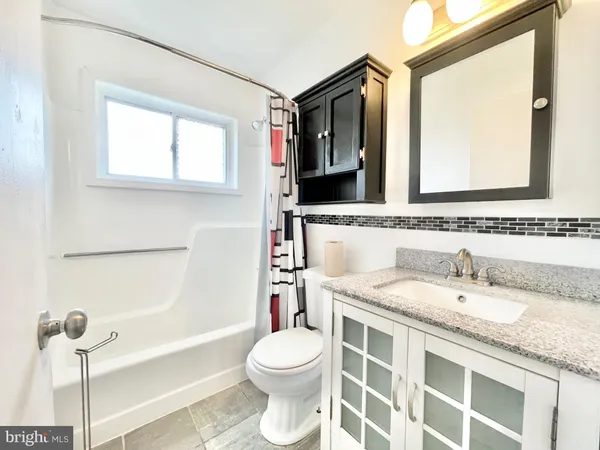 a bathroom with a granite countertop sink mirror vanity and toilet