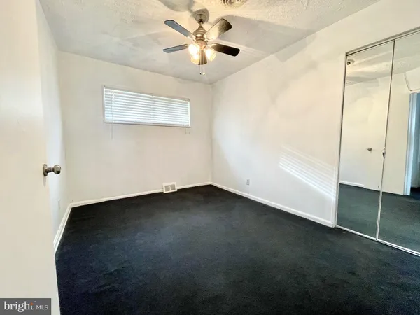 an empty room with a ceiling fan and a window
