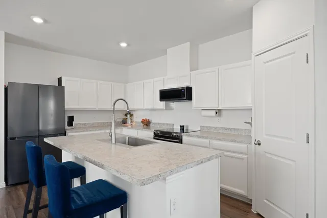 a kitchen with a sink a stove and chairs