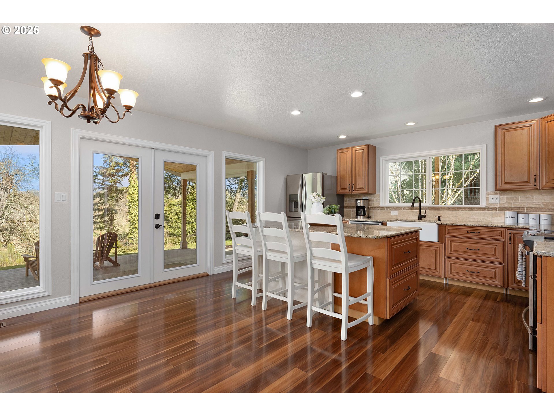 3993 Melqua Road Roseburg, OR 97471 - Photo 25 of 48 a kitchen with stainless steel appliances kitchen island granite countertop a stove a refrigerator a sink a dining table and chairs with wooden floor