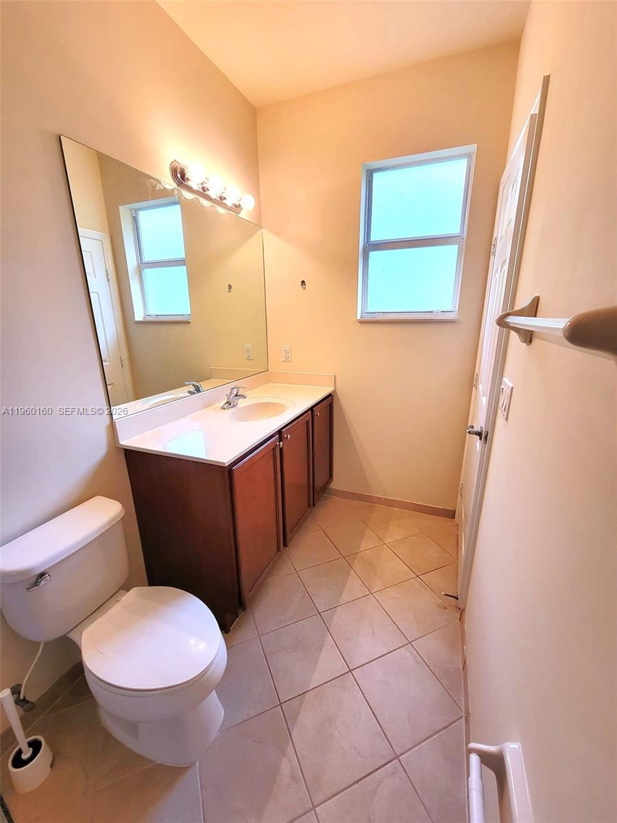 9031 Southwest 227th Street, Unit 5 Cutler Bay, FL 33190 - Photo 18 of 21 a bathroom with a sink a toilet a mirror and vanity