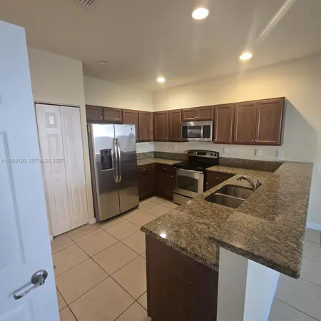 a kitchen with stainless steel appliances granite countertop a sink a stove a refrigerator and a refrigerator