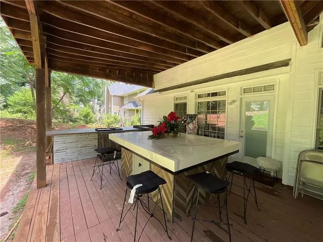 a view of a patio with table and chairs with wooden floor and fence with a barbeque grill