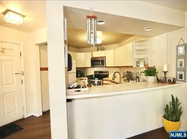 a view of a kitchen with kitchen island granite countertop a sink appliances cabinets and wooden floor