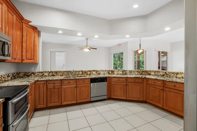 a large kitchen with stainless steel appliances granite countertop a stove top oven a sink dishwasher and granite countertops