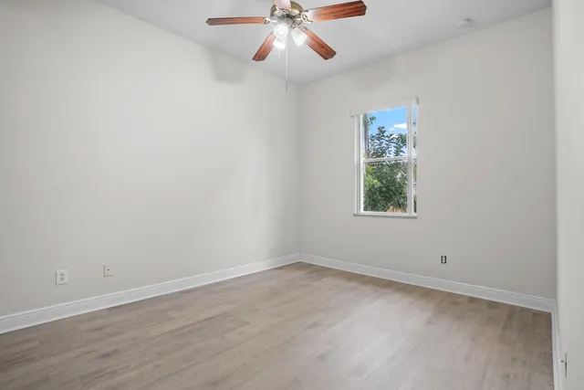an empty room with a window and a fan