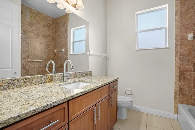a bathroom with a granite countertop sink a toilet and a mirror