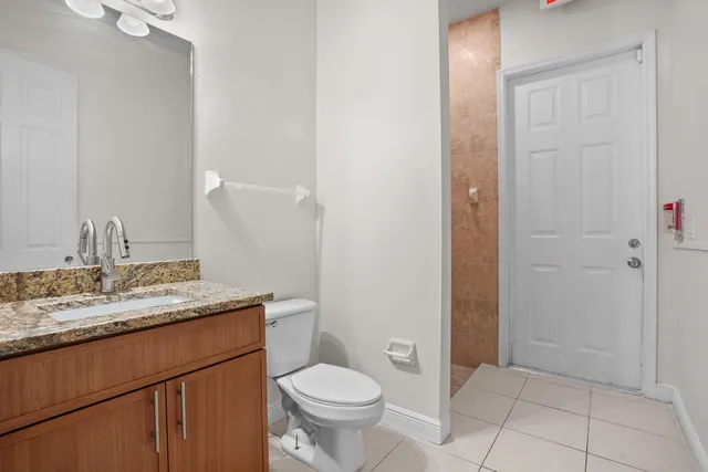 a bathroom with a granite countertop sink a toilet and a mirror