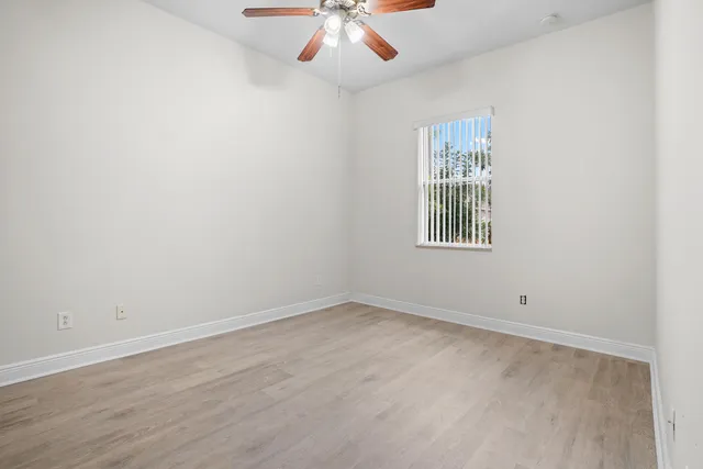 an empty room with windows and fan