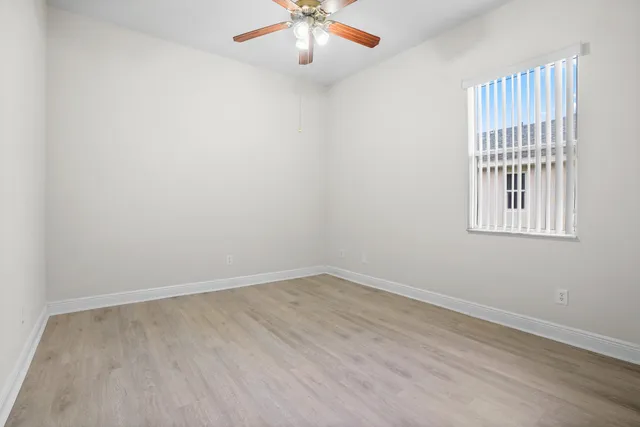 an empty room with windows and fan