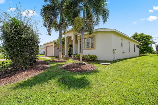 a view of a white house with a big yard and palm trees