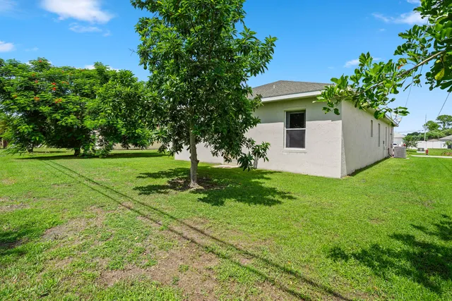 a view of a yard in front of a house with plants and large trees