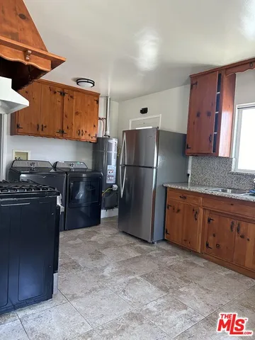 a kitchen with stainless steel appliances granite countertop a refrigerator a stove and a sink