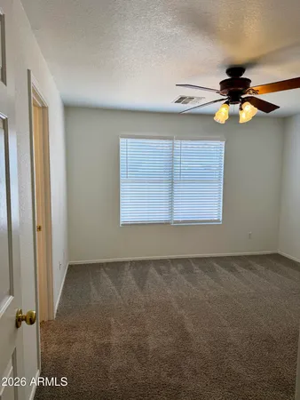 an empty room with windows and fan