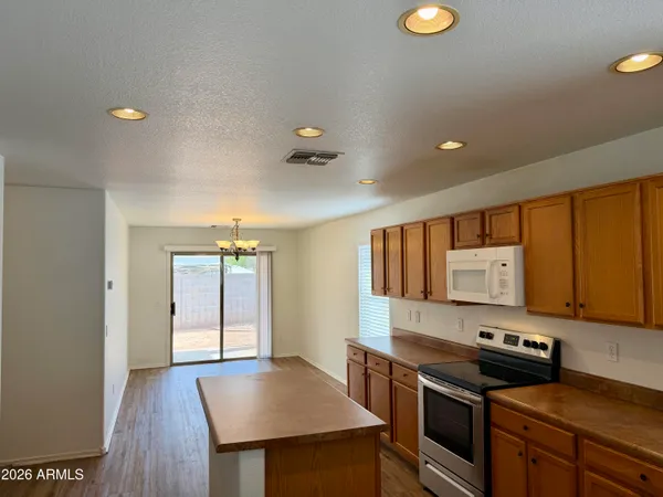 a kitchen with stainless steel appliances granite countertop a stove a sink dishwasher and a refrigerator with wooden floor