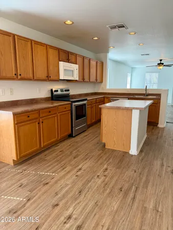 a large kitchen with stainless steel appliances granite countertop a stove top oven a sink and dishwasher with wooden floor
