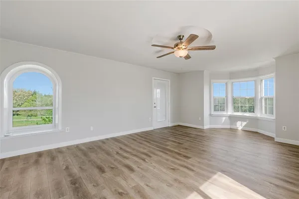 a view of empty room with wooden floor and fan