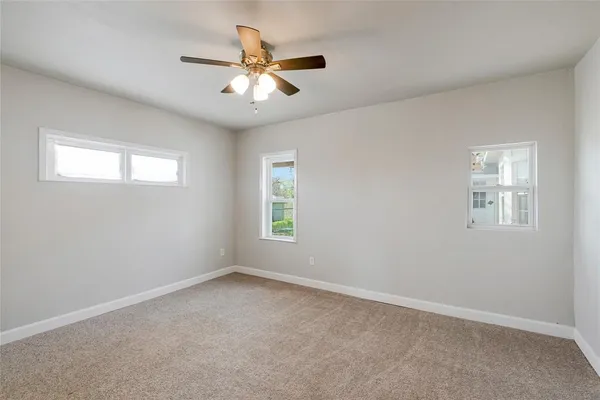 an empty room with windows and fan