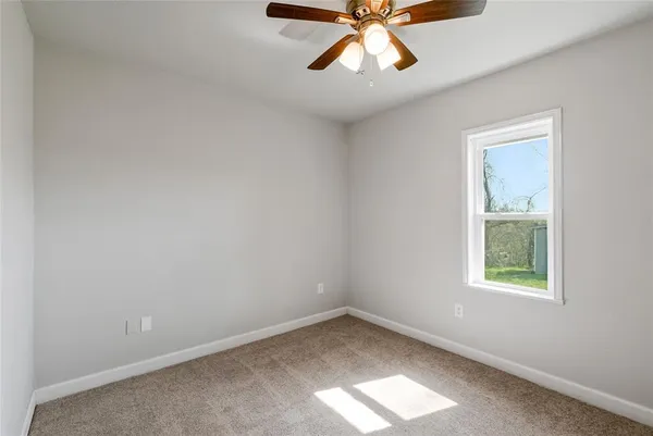 an empty room with a window and a fan