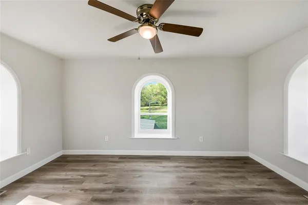 a view of an empty room with window and wooden floor