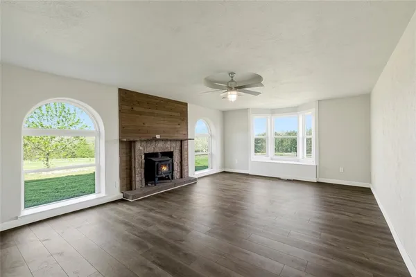 an empty room with windows a fireplace and wooden floor