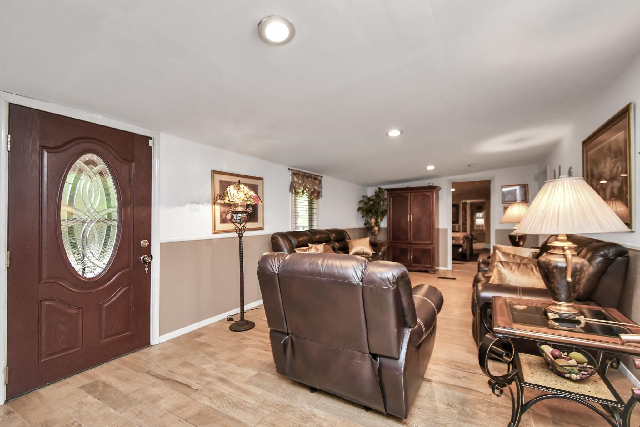 24998 Sorters Road Porter, TX 77365 - Photo 19 of 39 a living room with furniture a chandelier a mirror and a flat screen tv
