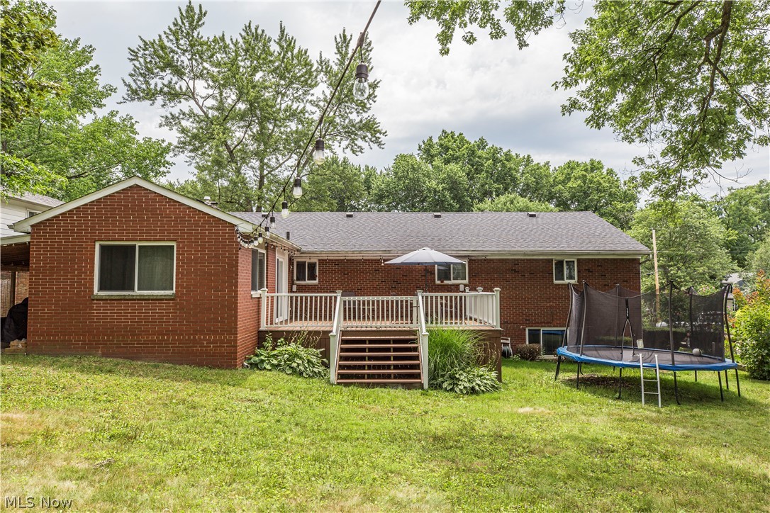 2095 Wyndham Road Akron, OH 44313 - Photo 31 of 40 Rear view of property with a yard, a trampoline, and a wooden deck